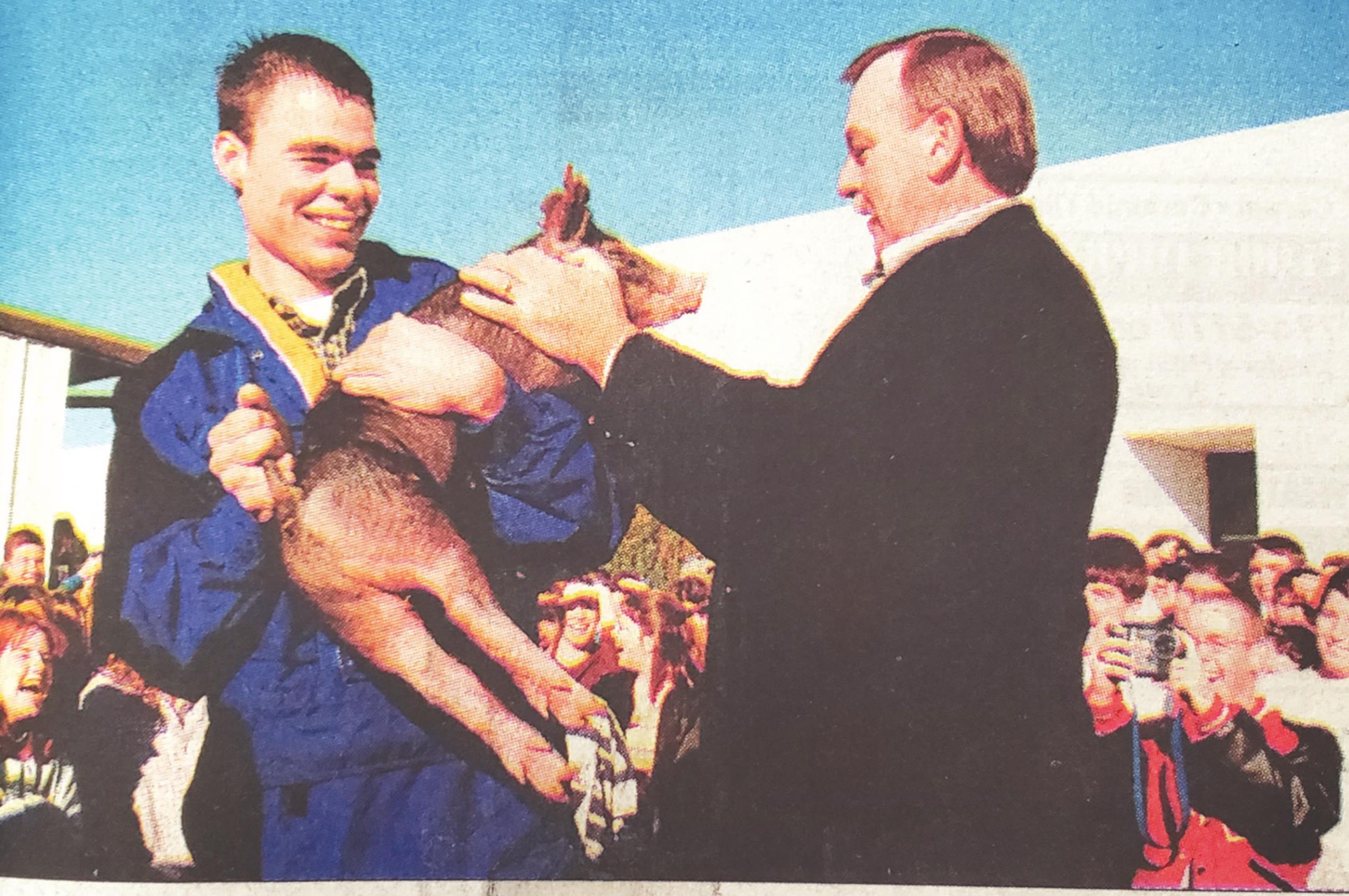 Jarrod Burton holds on tight as Weatherford High School teacher Dennis Seifried gets ready to kiss a pis as the finale to National DECA Week. Each teacher collected money in their classrooms and Seifried was in first place with $85.86. The money was used to fund the organization’s annual Angel Tree. This picture can be found in the November 19, 2000, edition of the Weatherford Daily News.