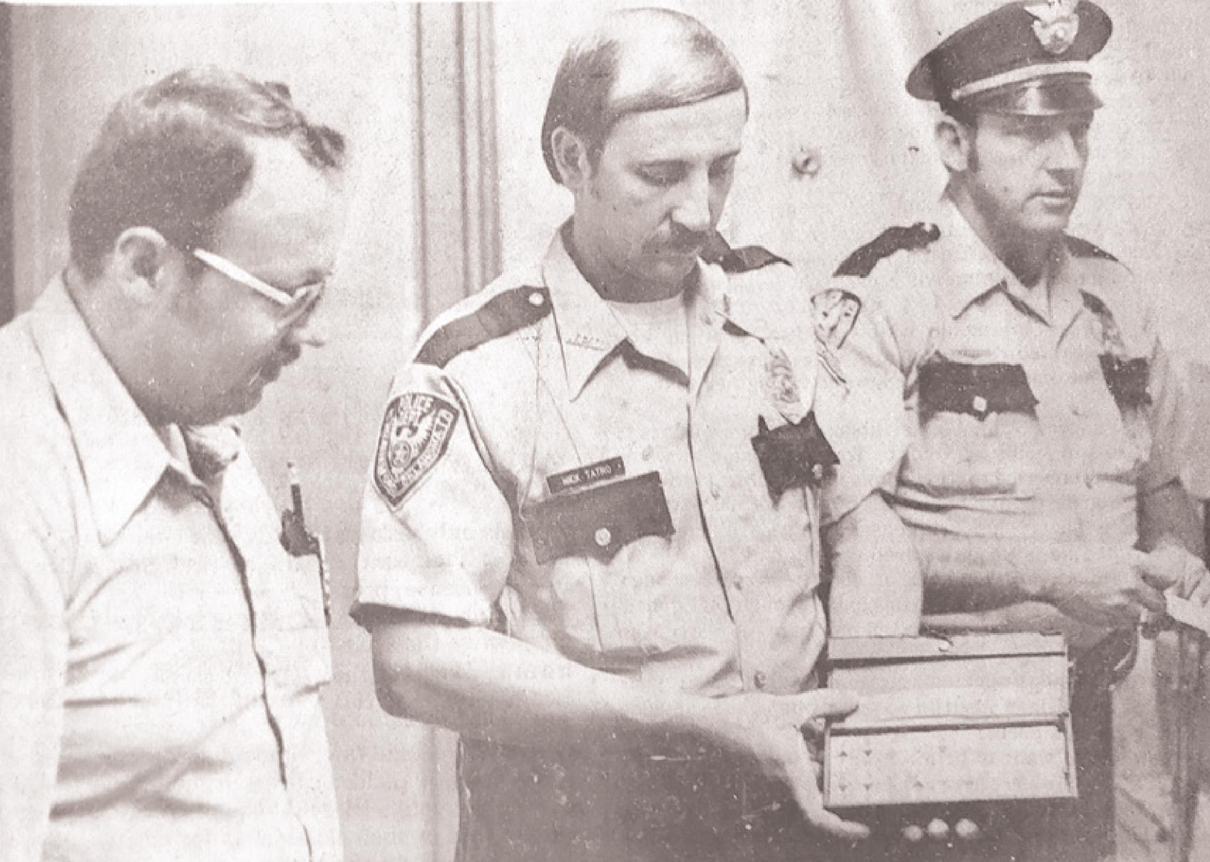 Det. Sgt. Randy Cox, left, and Patrolman Donnie Evans, right, look at some of the evidence from the nearly $25,000 worth of property recovered during an investigation resulting from officer Nick Tatro’s arrest earlier in the week. This picture can be found in the May 18, 1980, edition of the Weatherford Daily News.
