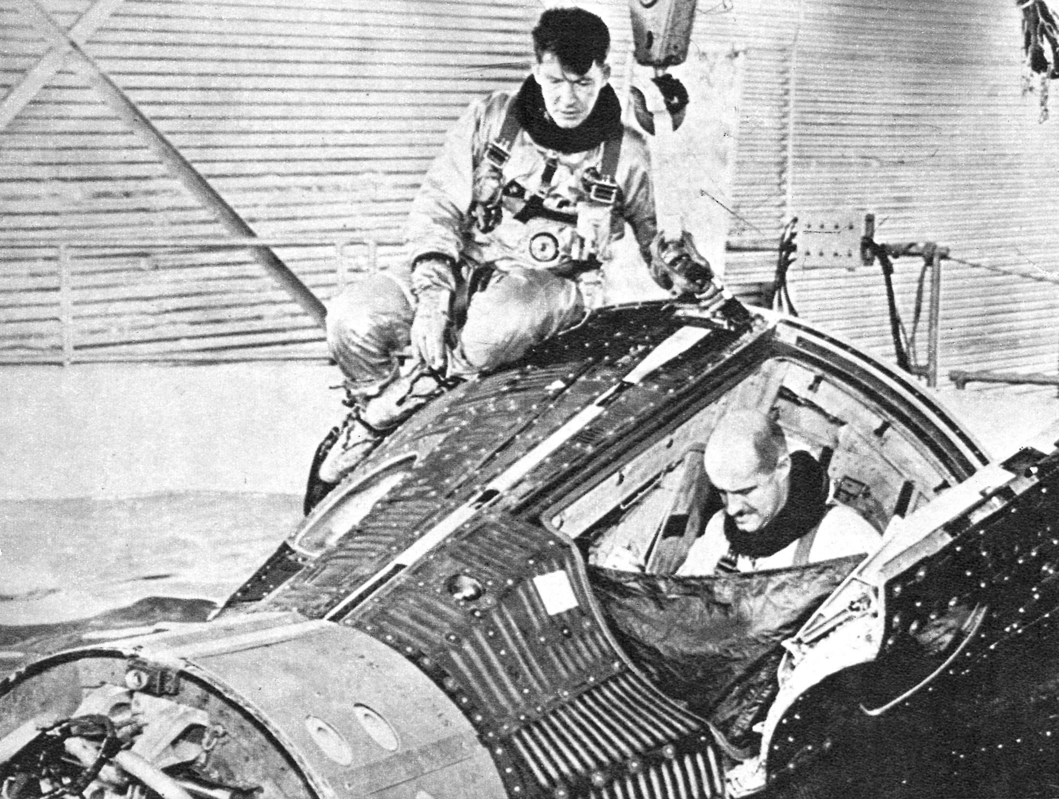 During training, Schirra balances the Gemini capsule while Stafford, right, his co-pilot, prepares to climb out of the capsule.