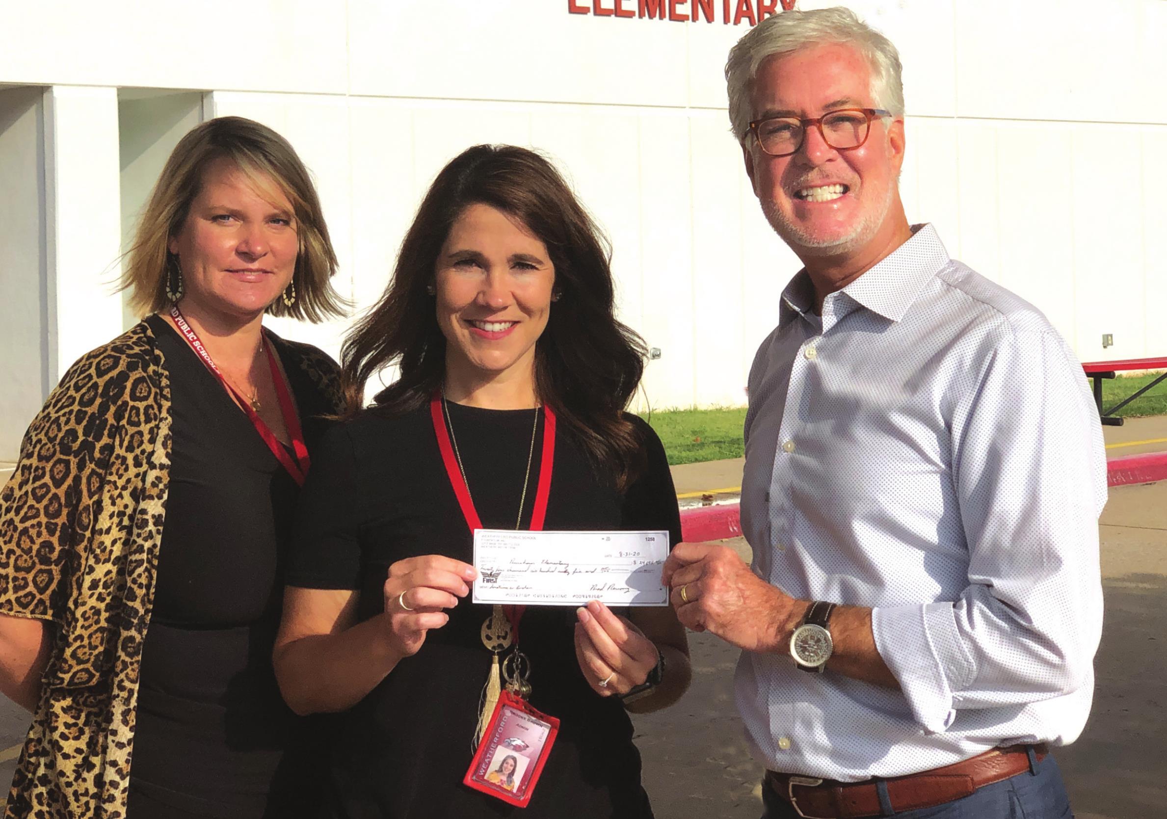 Weatherford Daily News Publisher Phillip Reid, right, hands Brooke Brown and Dru Svitak a check for $25,000. Money was raised with donations from the WDN’s half-price circulation drive, with $5 of every subscription renewal being given to Burcham Elementary’s vitual carnival and community drive. Timothy Comstock/WDN
