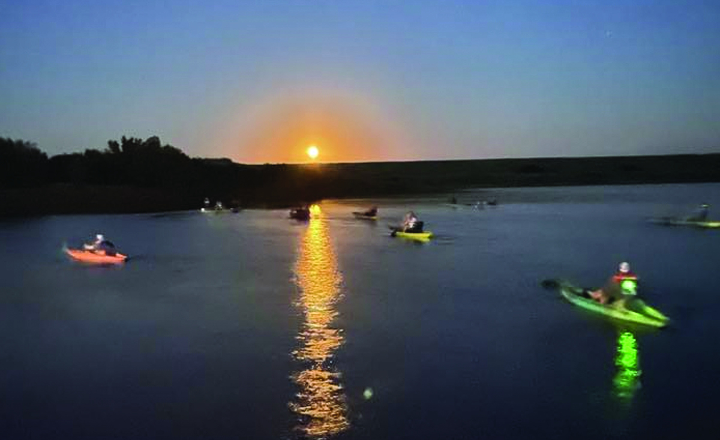 Attendees enjoy watching the sun go down during a full moon paddle at Crowder Lake. Provided