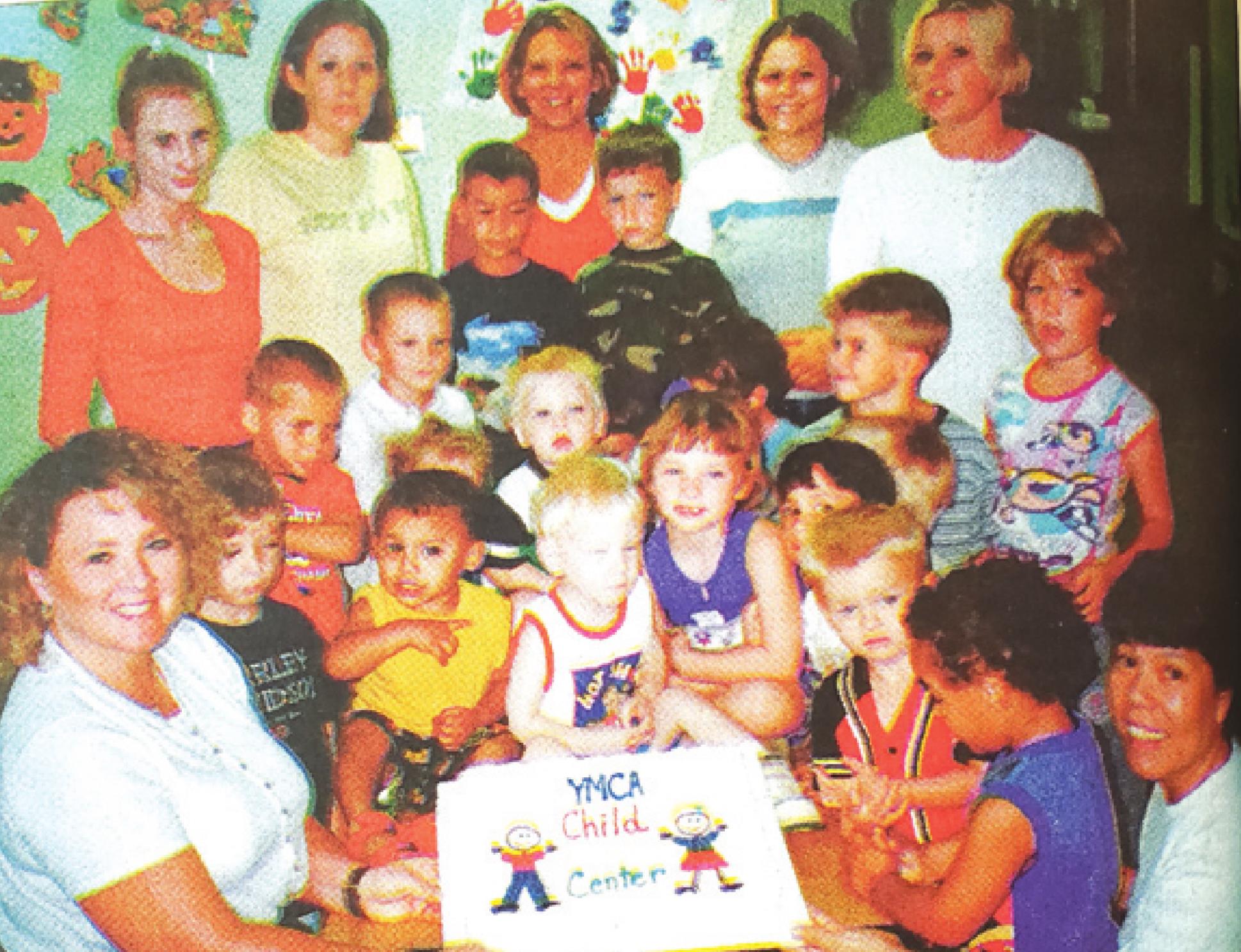 Former YMCA Child Development Center Director Sharbee Heinrichs, bottom left, celebrates the opening of the center with staff and students.