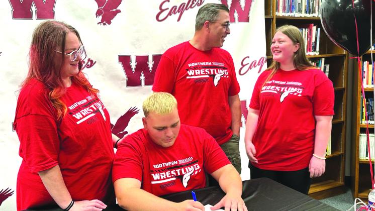 ► Avry Nailon, second from left, signs Wednesday to attend Northern Oklahoma College on a wrestling scholarship as the Nailon family watches. Shown here, from left, are his mother Vanessa, Avry, his father Bobby, and his sister Mabry. Tyler Bryson/WDN